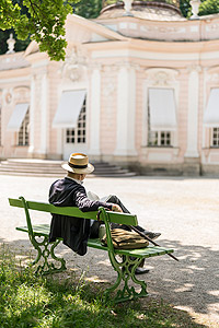 Parkbesucher auf einer Bank vor der Amalienburg